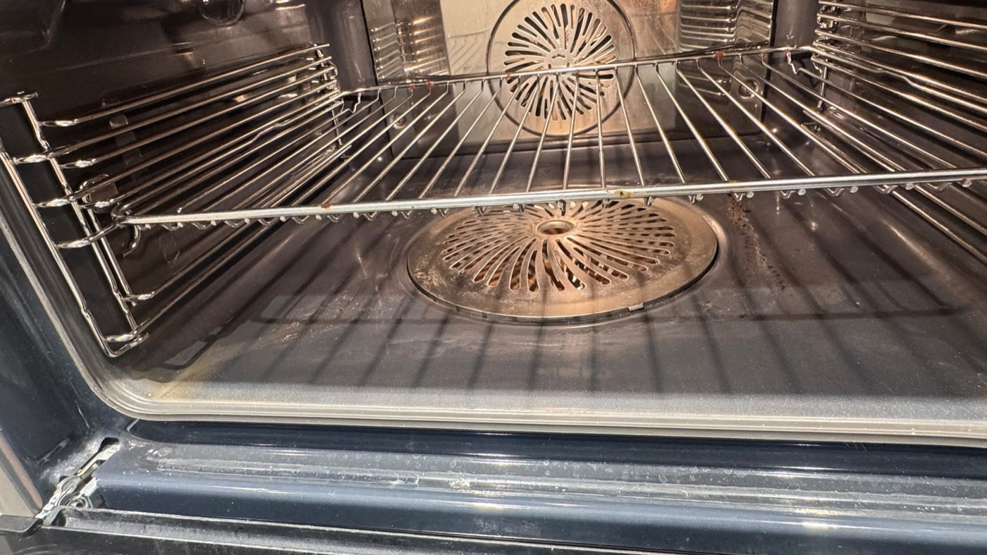 Backofen vor der Reinigung mit eingebrannten Rückständen an Blech, Rost und Scheibe