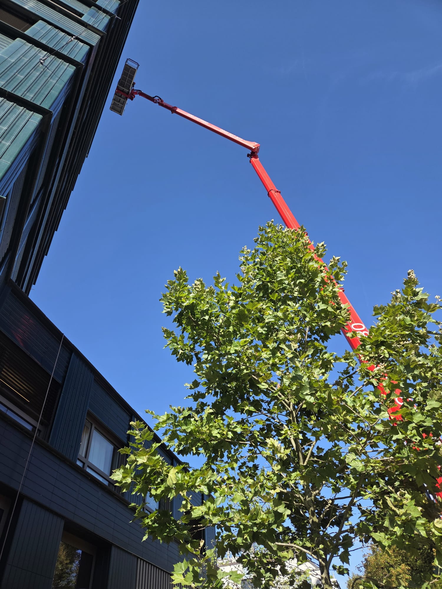 Arbeitskorb der Hubarbeitsbühne bei der Reinigung von Fensterlamellen an einem Hochhaus in Zürich