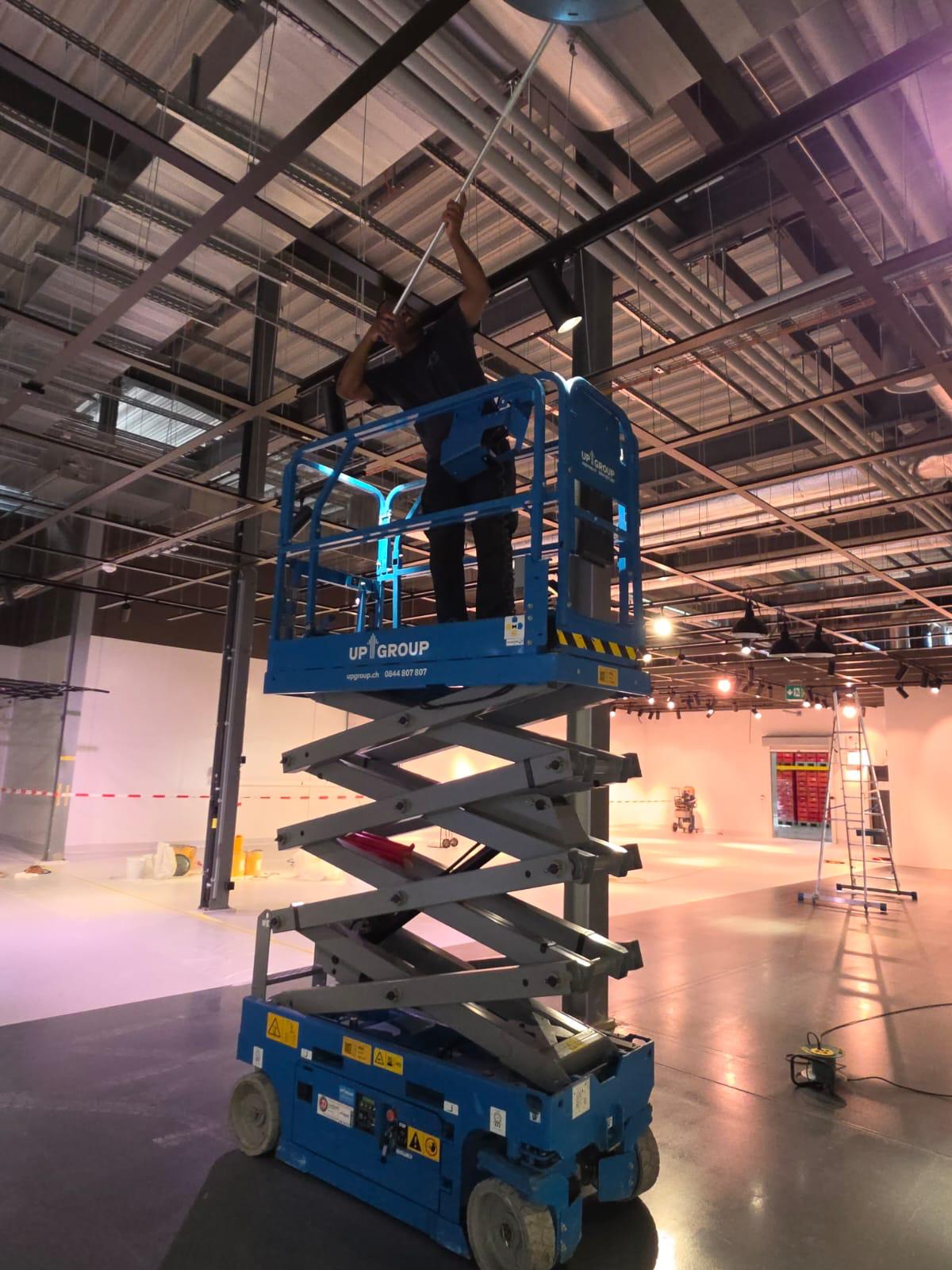 Mitarbeiter von ABC FACILITY Services reinigt auf einer Scherenbühne die Deckenträger einer Markthalle